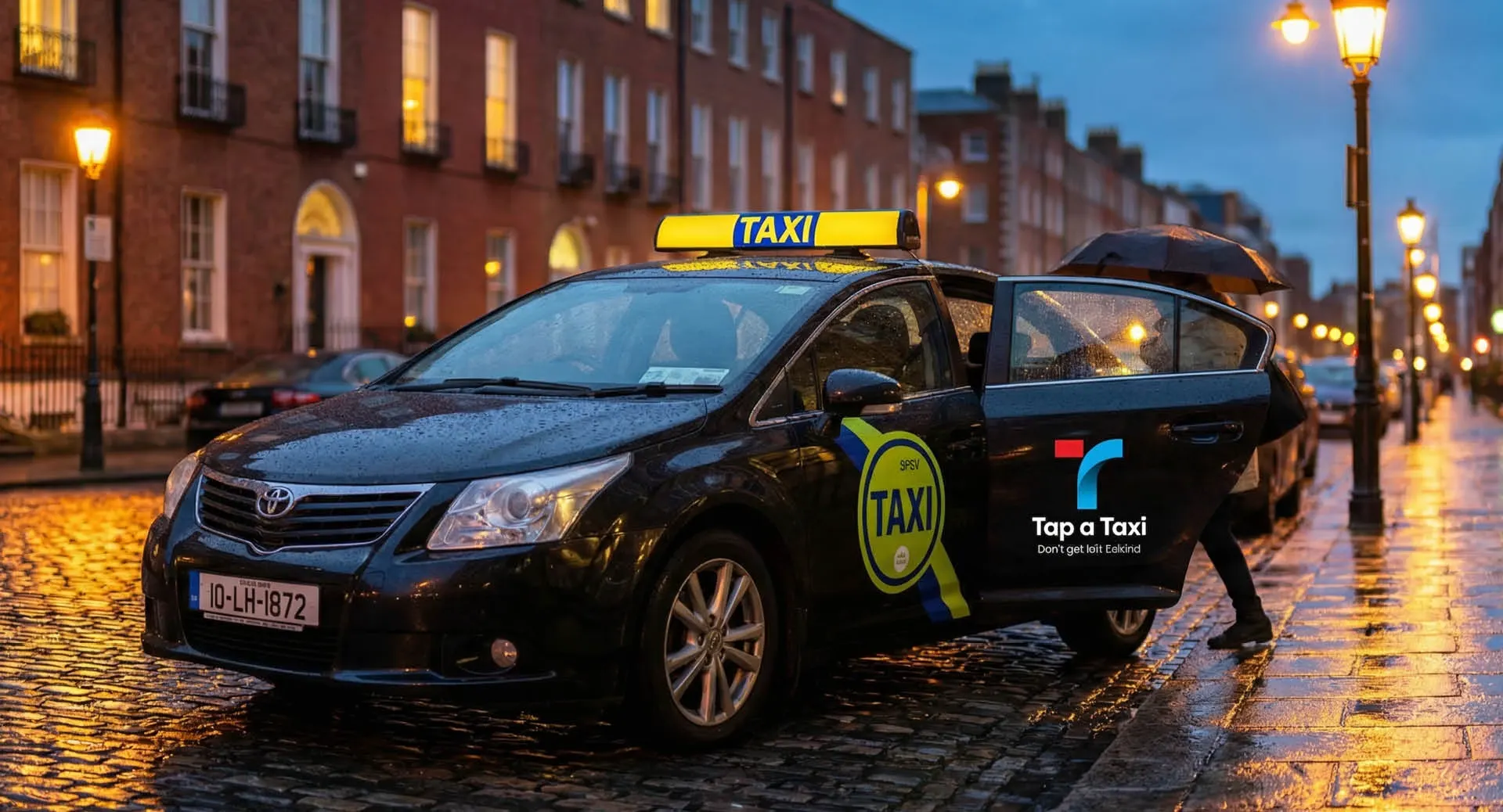 Black Dublin taxi with the Tap a Taxi logo on the door, on a wet street at dusk